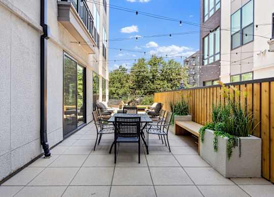 A patio with a table and chairs is surrounded by a wooden fence.