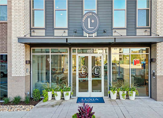The entrance to a Lululemon store with a blue doormat and potted plants.