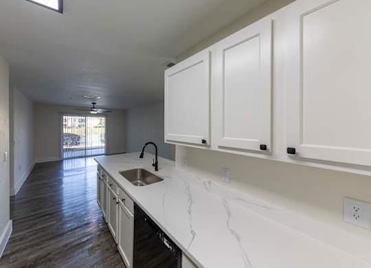 A kitchen with white cabinets and a marble countertop.