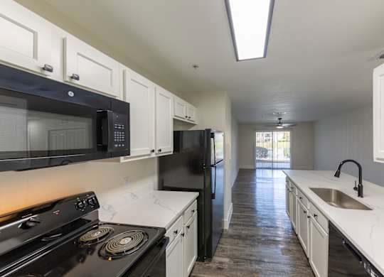 A kitchen with black appliances and white cabinets.