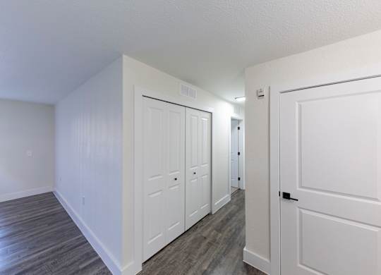 A hallway with white doors and wood floors.