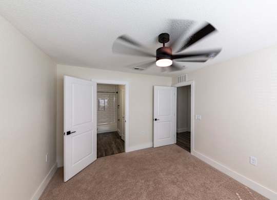A room with a ceiling fan and two doors.