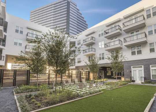 A modern apartment complex with a well-maintained garden in the foreground.