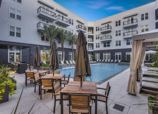 A poolside area with chairs and umbrellas in front of a building.