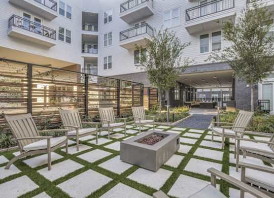 A patio with chairs and a fire pit in front of a building.