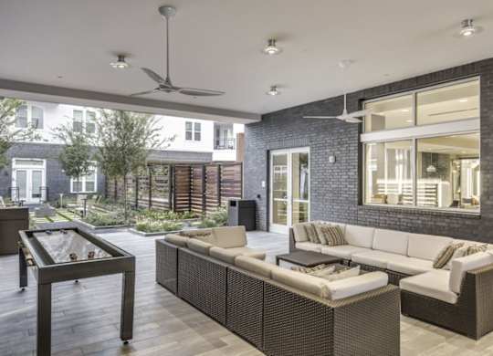A modern outdoor patio with a wicker sofa and coffee table.