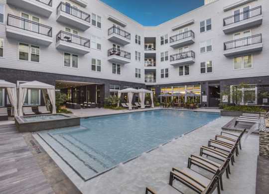 A large outdoor pool surrounded by wooden deck chairs and lounge areas.