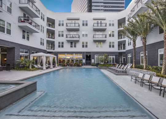 A large swimming pool in front of a building with a white exterior.
