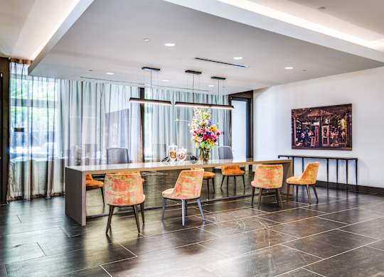 A dining room with a table set for six with orange chairs.