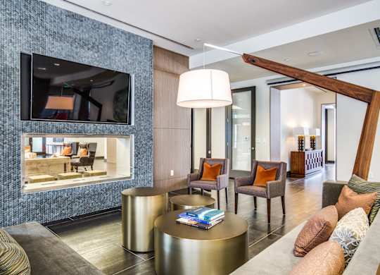 A living room with a grey sofa, a round gold coffee table, and a large mirror on the wall.