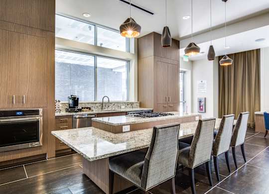 A modern kitchen with a marble countertop and a row of chairs.