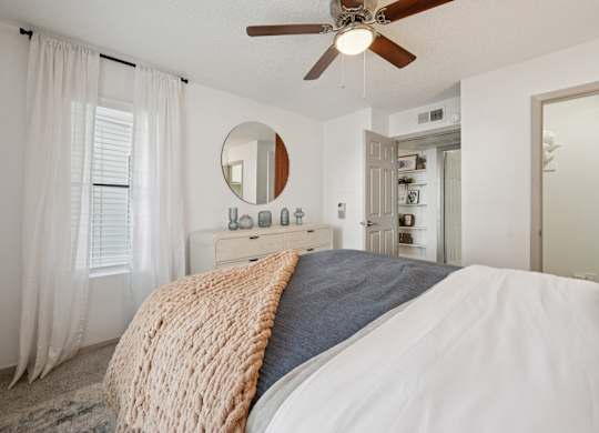 A bedroom with a large bed and a ceiling fan.