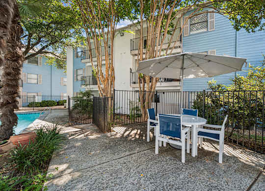 A patio with a table and chairs and an umbrella.