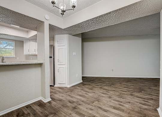 a kitchen and living room with hardwood floors and a chandelier