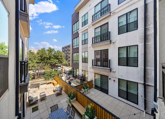 A balcony with a table and chairs overlooks a courtyard.