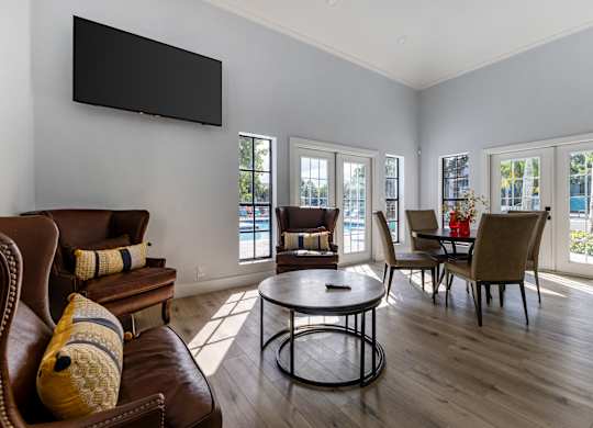 A living room with a brown leather couch and a black television mounted on the wall.