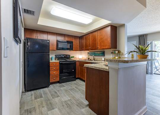 A kitchen with a black refrigerator and wooden cabinets.