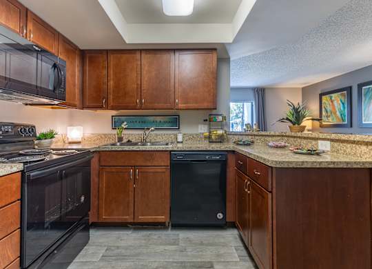 A kitchen with dark wood cabinets and black appliances.