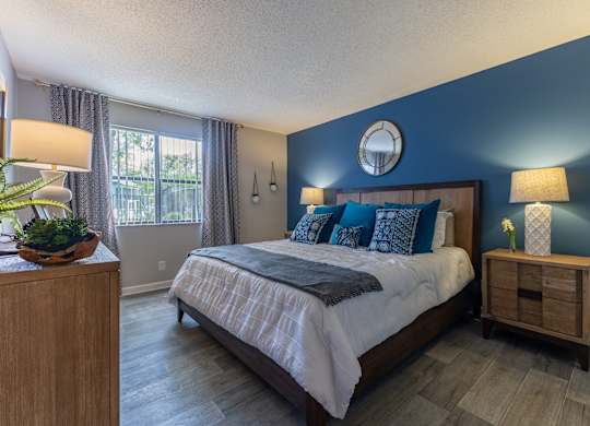 A bedroom with a large bed and a wooden nightstand.