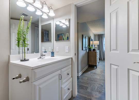 A white bathroom with a vanity and a mirror.