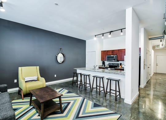 living room with a kitchen in the background and a yellow chair in the foreground