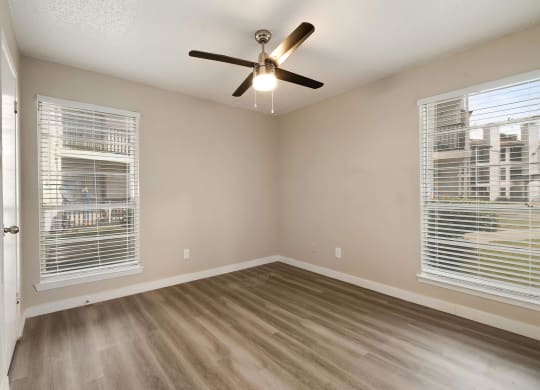 a bedroom with two windows and a ceiling fan