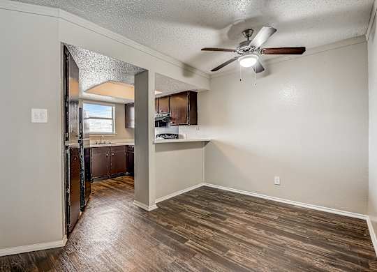 a bedroom with a ceiling fan and a kitchen in the background