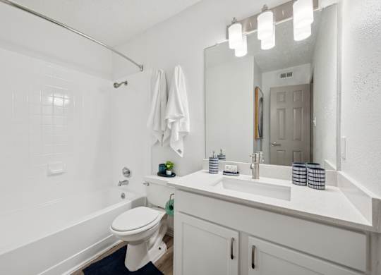 A white bathroom with a toilet, sink, and mirror.