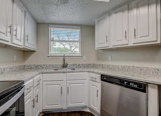 a kitchen with white cabinets and granite counter tops