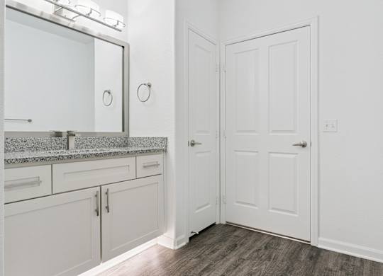 A white bathroom with a vanity and a door.