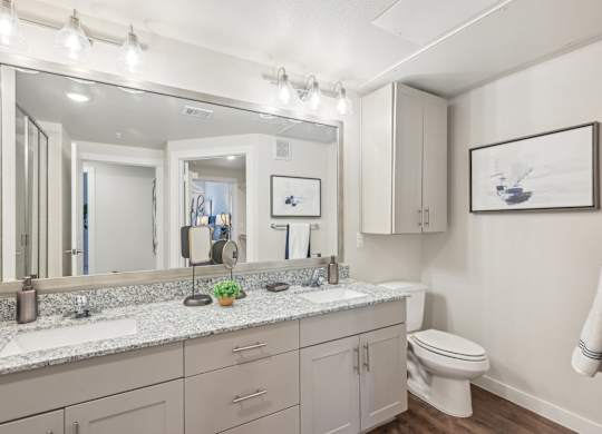 A bathroom with a large mirror, a toilet, and a sink.