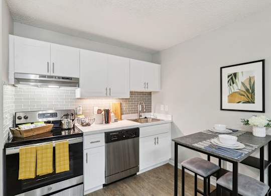 A modern kitchen with white cabinets and a black stove top.