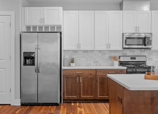 a kitchen with white cabinets and a stainless steel refrigerator
