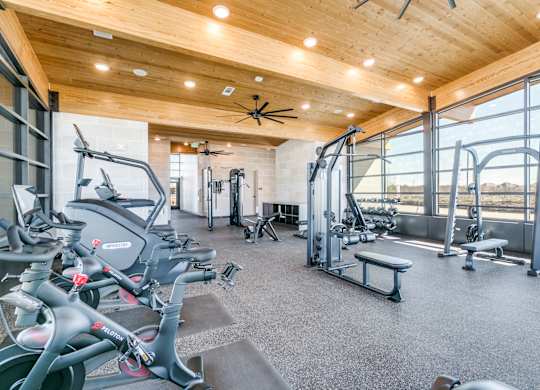A gym with a variety of exercise equipment including treadmills, stationary bikes, and weight machines.