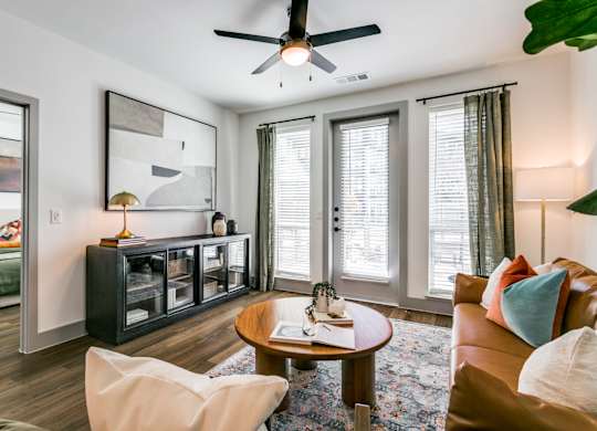 A living room with a brown leather couch, a wooden coffee table, and a ceiling fan.