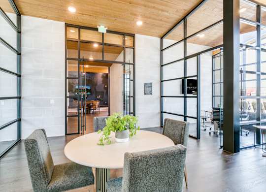 A round table with four chairs around it in a room with a glass wall.