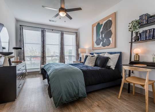 A bedroom with a bed, a chair, and a ceiling fan.