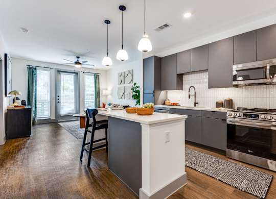 A modern kitchen with a white island and stainless steel appliances.