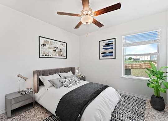 A bedroom with a bed, nightstand, and a ceiling fan.