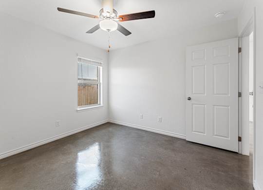 an empty room with white walls and a ceiling fan