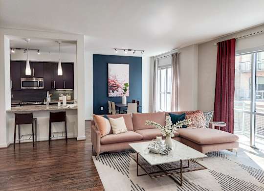 A living room with a couch, a coffee table, and a kitchen area in the background.