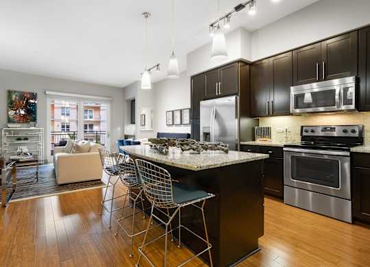 an open kitchen and living room with a marble counter top