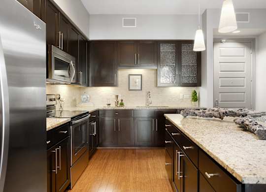a kitchen with black cabinets and a marble counter top