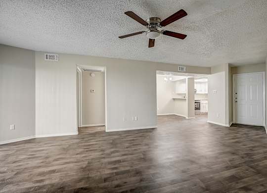 an empty living room with a ceiling fan