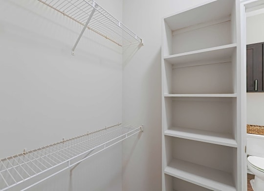 a walk in closet with shelves and a toilet in it