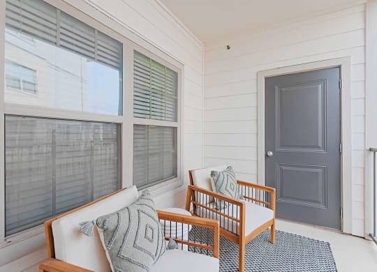 a front porch with a couch and chairs and a door