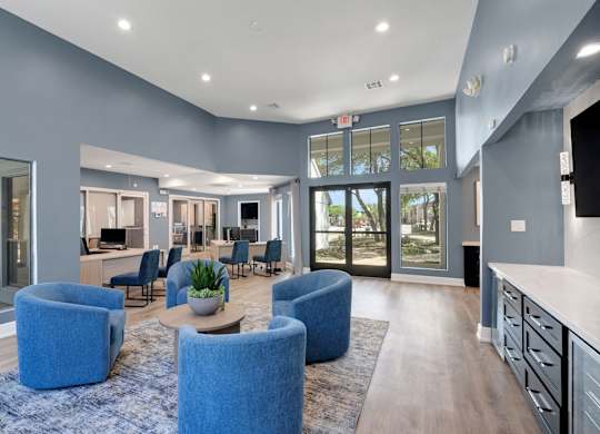 A spacious living room with blue chairs and a wooden floor.