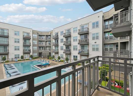 A view of a pool and apartment buildings from a balcony.