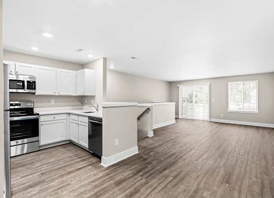 the living room and kitchen of a new home with white walls and wood flooring