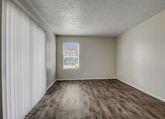 an empty living room with a window and curtains